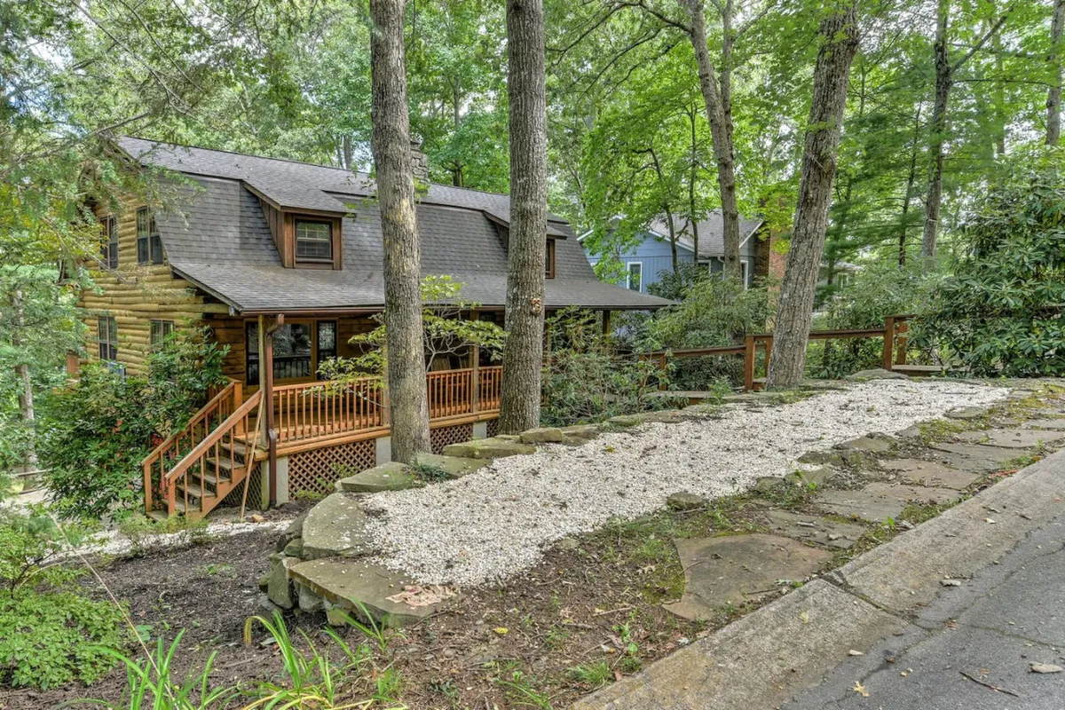 This photo captures the log cabin's rustic architecture nestled among mature trees, with a spacious wooden deck inviting families to gather outside. The surrounding woodland hints at nature walks, while the deck itself is perfect for outdoor play and relaxation after a day of exploring local attractions.