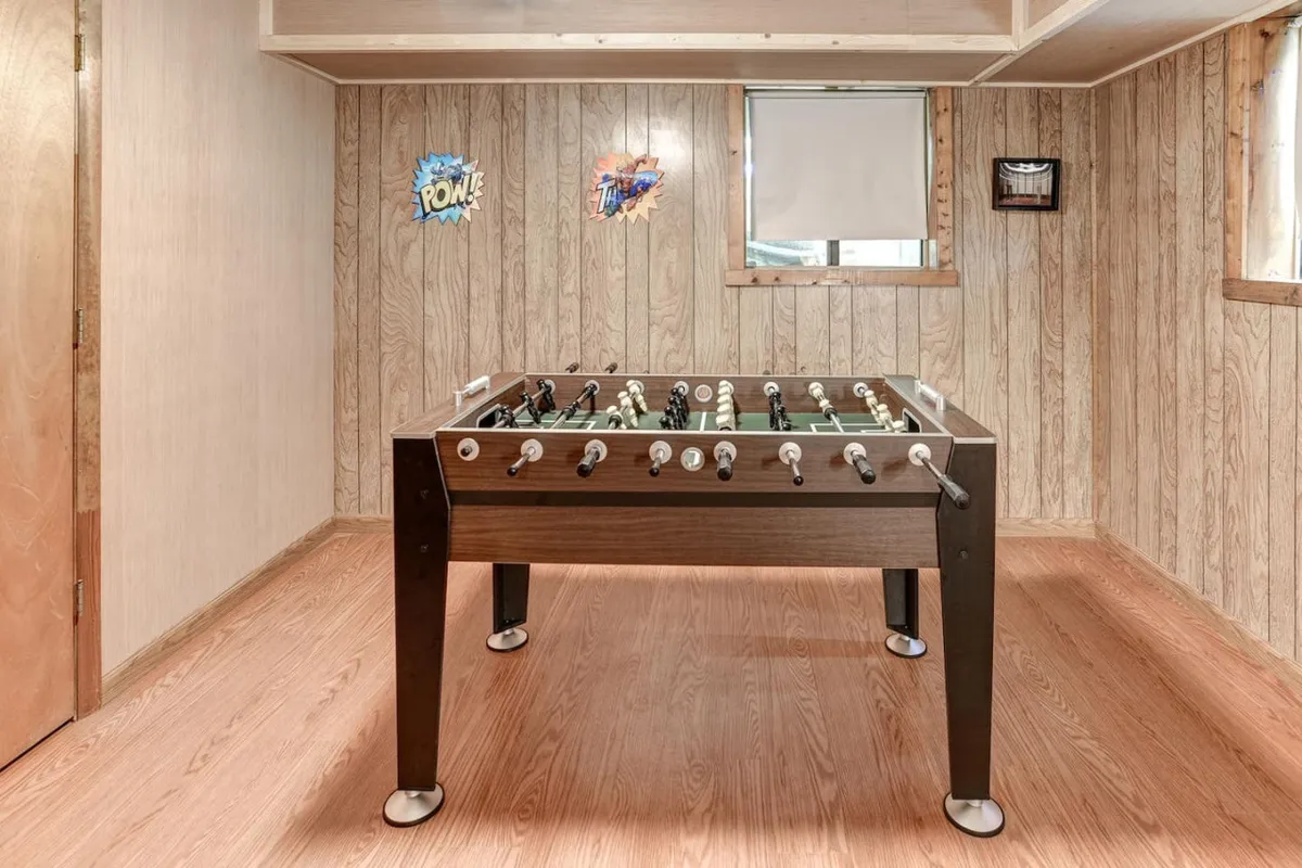 A vibrant game area with a foosball table as the centerpiece, complemented by playful comic-style wall art. The atmosphere is energetic and relaxed, emphasizing social interaction and fun activities for kids.